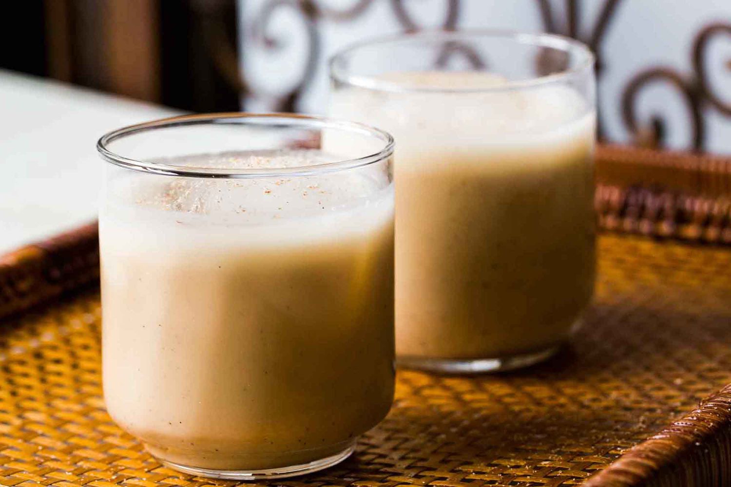 Two glasses of coquito with nutmeg on top
